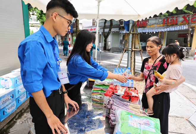 Các tình nguyện viên Thủ đô cung cấp nước uống, đồ ăn nhẹ, quạt giấy cho người dân. (Ảnh: Minh Đức/TTXVN) ttxvn_tinh nguyen vien 2.jpg