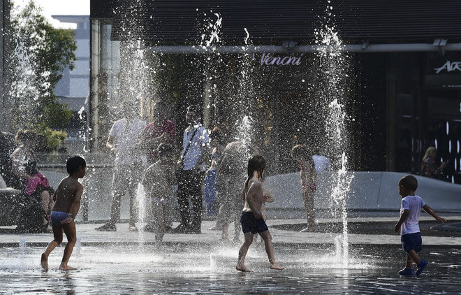 Trẻ em chơi đùa bên vòi phun nước để tránh nắng nóng tại Milan, Italy, ngày 26/6/2019. (Ảnh: AFP/ TTXVN) LHQ: El Nino có thể gây nắng nóng kỷ lục trong vài tháng tới ảnh 1