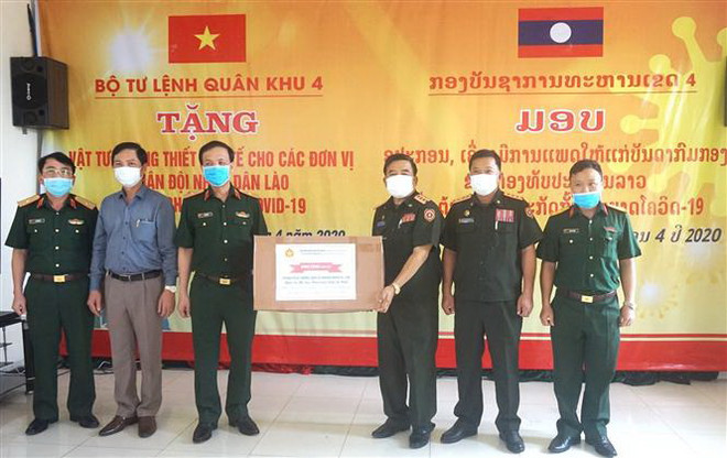 Đại diện lãnh đạo Bộ Tư lệnh Quân khu 4 (bên trái) trao tặng vật tư y tế cho đại diện quân đội Lào. (Ảnh: TTXVN) Trao tặng quân đội Lào vật tư y tế phòng, chống dịch COVID-19 ảnh 1