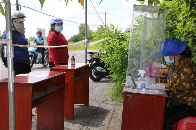 Người dân khai báo y tế tại chốt kiểm soát 832, đoạn đường giáp ranh 'vùng xanh' huyện Tân Trụ và 'vùng cam' huyện Bến Lức (Long An). (Ảnh: Thanh Bình/TTXVN) Ngày đầu nới lỏng giãn cách ở Long An: Có nơi chen lấn mua hàng hóa ảnh 2