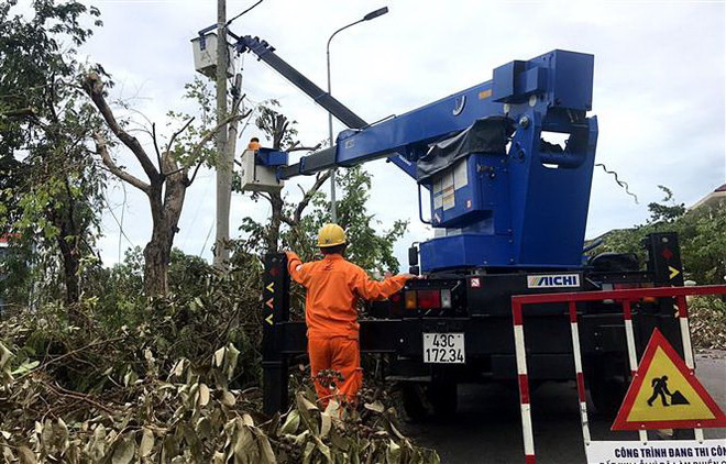 Công nhân ngành điện tranh thủ từng phút để khôi phục điện lưới. (Ảnh: Tường Vi/TTXVN) Khắc phục sự cố lưới điện sau cơn bão số 5 tại Thừa Thiên-Huế ảnh 2