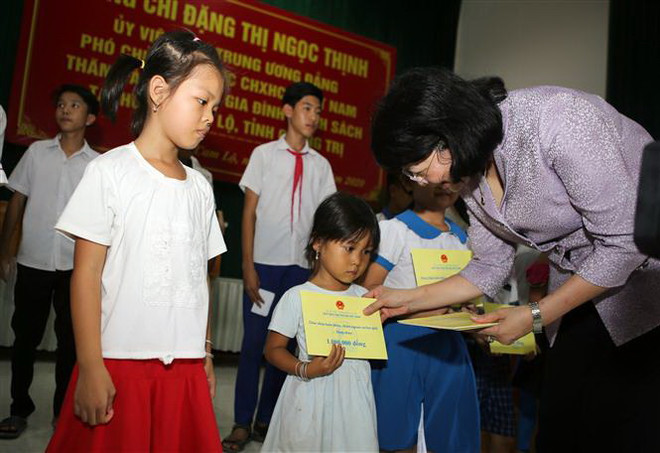 Phó Chủ tịch nước Đặng Thị Ngọc Thịnh tặng quà cho con gia đình chính sách tại huyện Cam Lộ. (Ảnh: Hồ Cầu/TTXVN) Phó Chủ tịch nước trao quà tặng các gia đình chính sách tại Quảng Trị ảnh 1