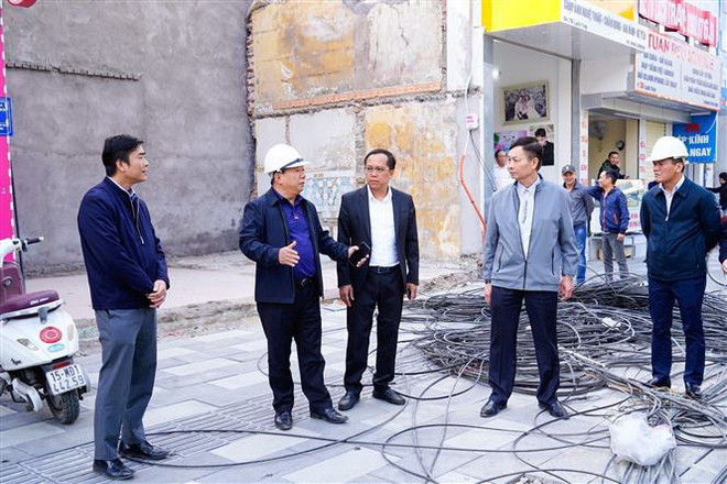 Phó Chủ tịch Ủy ban Nhân dân thành phố Hải Phòng Nguyễn Đức Thọ (thứ hai từ trái sang) kiểm tra các hạng mục tại đường Lạch Tray, quận Ngô Quyền. (Ảnh: TTXVN phát) 'Một cửa, một điểm' - cách làm sáng tạo trong giải phóng mặt bằng ảnh 3