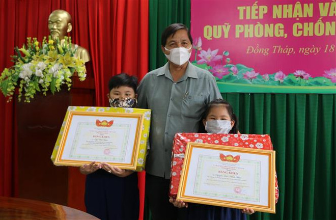 Ông Lê Thành Công, Trưởng Ban Dân vận Tỉnh ủy, Chủ tịch Ủy ban MTTQ Việt Nam tỉnh Đồng Tháp, biểu dương hành động nhân ái của hai em Nguyễn Quốc Minh Khuê (phải) và Ngô Vĩnh Bình (trái). (Ảnh: Chương Đài/TTXVN) Cụ ông 100 tuổi dành tiền mừng thọ ủng hộ công tác phòng, chống dịch ảnh 2