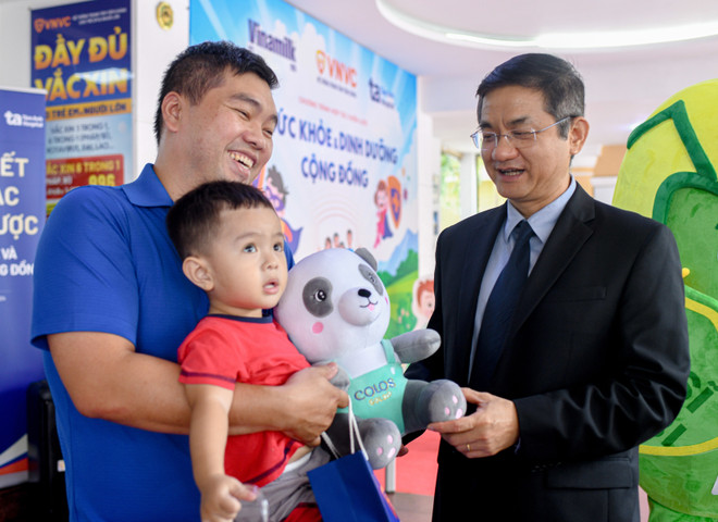 Ông Nguyễn Quang Trí – Giám đốc Điều hành Vinamilk, tặng quà cho các gia đình, các bé đến tiêm ngừa tại Trung tâm VNVC trong ngày kí kết hợp tác. (Ảnh: Vi Nam/Vietnam+) Hình 4a-VNM-VNVC.jpg
