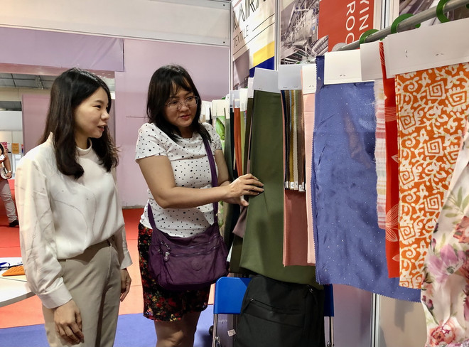 Khách tham quan tìm kiếm nguồn cung vải tại Triển lãm. (Ảnh: Mỹ Phương/TTXVN) ttxvn_trien lam det may 2.jpg