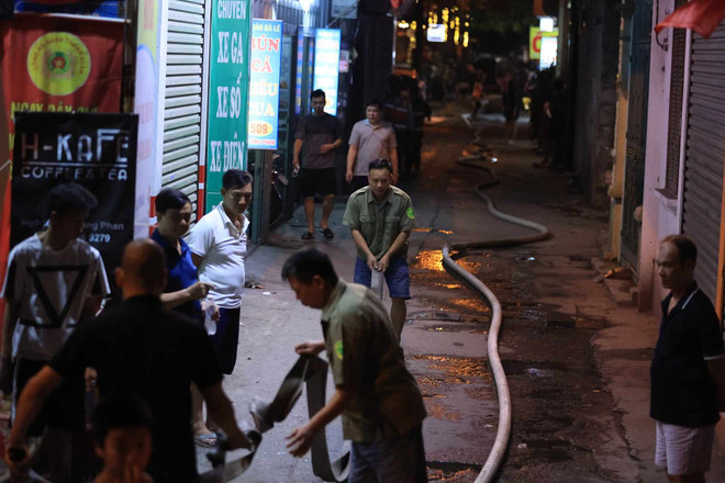 Ngõ nhỏ và sâu nên việc cứu hoả gặp nhiều khó khăn, cảnh sát đã phải dẫn đường dây nước vào hiện trường. (Ảnh: Hoài Nam/Vietnam+) vnp_2.jpeg