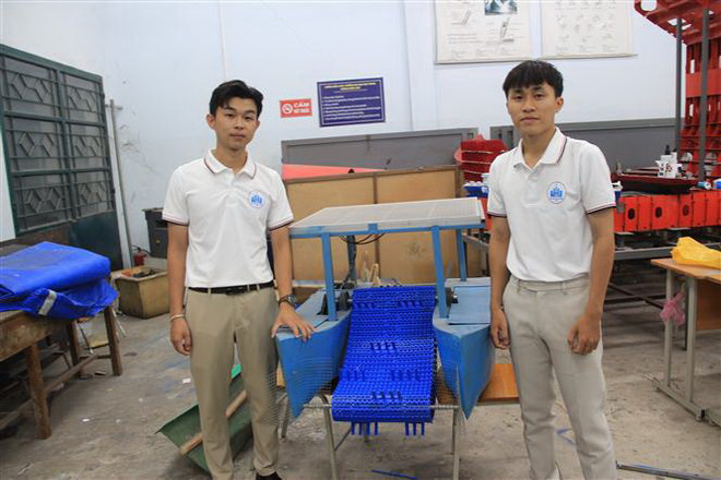Ngô Hoàng Thịnh (bên trái) với mô hình tàu vớt rác hai thân, tích hợp năng lượng mặt trời. (Ảnh: Phan Sáu/TTXVN) Sáng tạo mô hình máy vớt rác hai thân tích hợp năng lượng mặt trời ảnh 2