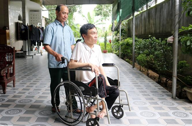 Thương binh Nguyễn Đình Duyên (bản Hốc, xã Châu Đình, huyện Quỳ Hợp, tỉnh Nghệ An) cùng người con trai bị nhiễm chất độc da cam. (Ảnh: Văn Tý/TTXVN) Ký ức hào hùng của dũng sỹ diệt Mỹ bắn rơi 6 máy bay địch ảnh 2