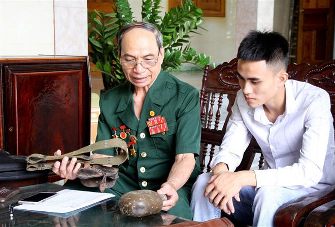 Thương binh Nguyễn Đình Duyên kể lại cho cháu nghe về những trận đánh oanh liệt của ông cùng đồng đội trong chiến tranh. (Ảnh: Văn Tý/TTXVN) Ký ức hào hùng của dũng sỹ diệt Mỹ bắn rơi 6 máy bay địch ảnh 1