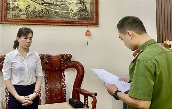 Cán bộ Phòng Cảnh sát điều tra tội phạm về tham nhũng, kinh tế, buôn lậu Công an tỉnh Cao Bằng tống đạt quyết định khởi tố bị can, lệnh bắt bị can để tạm giam đối với bà Hoàng Thị Xuyến, Giám đốc Ban quản lý dự án đầu tư và xây dựng huyện Bảo Lạc. (Ảnh: TTXVN phát) Cao Bằng: Bắt Giám đốc Ban quản lý dự án đầu tư và xây dựng Bảo Lạc ảnh 1