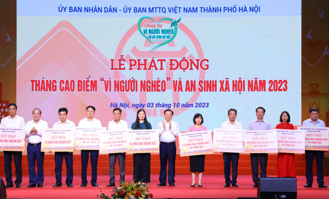 Bí thư Thành ủy Hà Nội Đinh Tiến Dũng và Phó Chủ tịch Ủy ban Trung ương Mặt trận Tổ quốc Việt Nam Hoàng Công Thủy trao hỗ trợ cho các hộ nghèo. (Ảnh: Văn Điệp/TTXVN) Hà Nội phát động Tháng Cao điểm 'Vì người nghèo và an sinh xã hội' ảnh 2