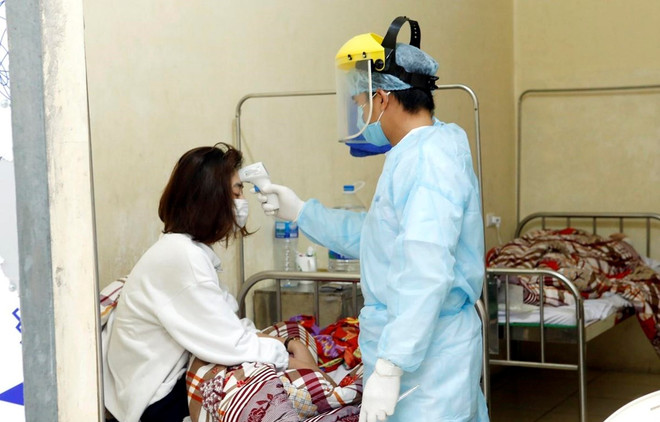 Nhân viên y tế kiểm tra thân nhiệt cho bệnh nhân được cách ly tại Trung tâm y tế huyện Bình Xuyên, tỉnh Vĩnh Phúc. (Ảnh: Dương Ngọc/TTXVN) Chuyện về 'chiến binh áo trắng' chống COVID-19 ở tâm dịch Bình Xuyên ảnh 2