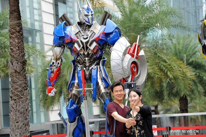 Du khách chụp ảnh với mô hình nhân vật trong phim 'Transformers.' (Nguồn: News.xinhuanet.com) Thái Lan kết hợp đền chùa và siêu anh hùng để hút khách du lịch ảnh 1