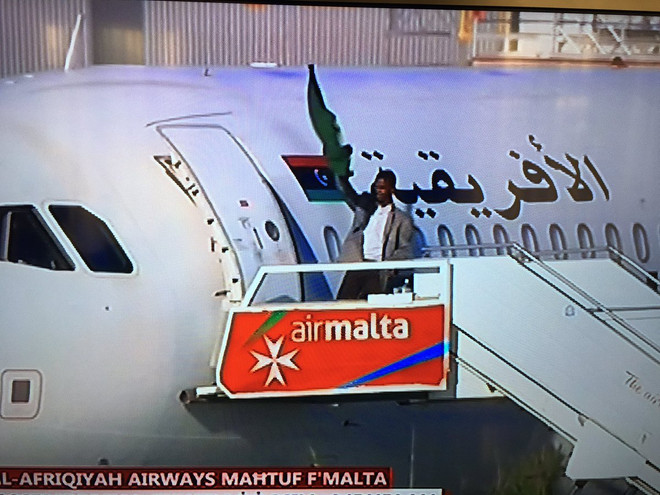 Một trong hai tên không tặc xuất hiện với lá cờ màu xanh của ông Gaddafi Thủ tướng Malta thông báo 118 người trên máy bay Libya đã an toàn ảnh 1