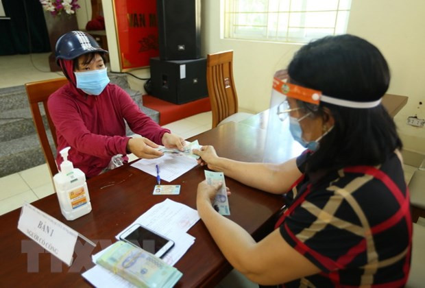 Người lao động gặp khó khăn nhận tiền hỗ trợ. (Ảnh minh họa: Hoàng Hiếu/TTXVN) Tháo gỡ điểm nghẽn để phát triển sản xuất, đảm bảo an sinh xã hội ảnh 2