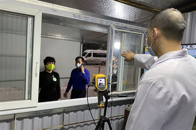 Mọi người dân và du khách được đo thân nhiệt trước khi vào hoặc ra khỏi vùng biên giới Móng Cái. (Ảnh: Văn Đức/TTXVN) COVID-19: Quảng Ninh đã đón và cách ly tập trung hơn 2.300 người ảnh 1