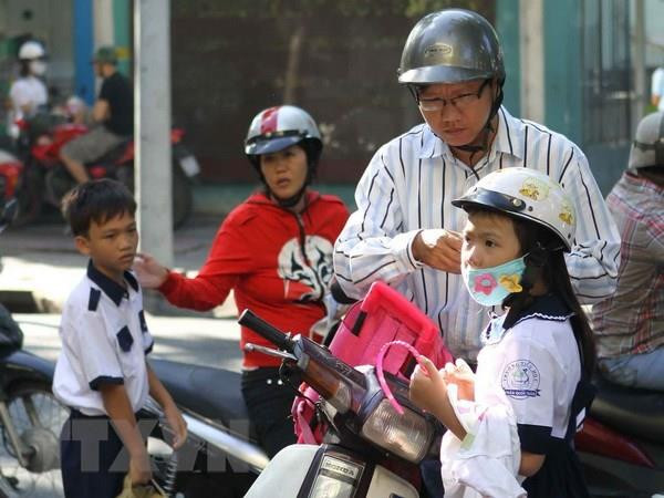 Phụ huynh đội mũ bảo hiểm cho trẻ khi tham gia giao thông. (Ảnh: TTXVN) Tập trung xử lý hành vi chở trẻ em đi xe máy không đội mũ bảo hiểm ảnh 1