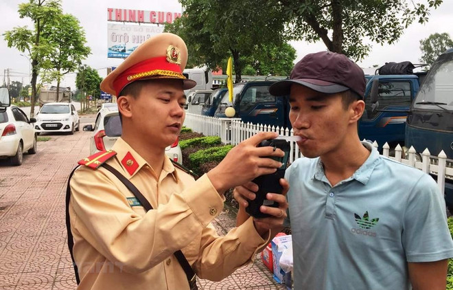 Cảnh sát giao thông tiến hành kiểm tra đo nồng độ cồn đối với lái xe. (Ảnh: Việt Hùng/Vietnam+) Thổi nồng độ cồn có thể lây nhiễm virus corona hay không? ảnh 1