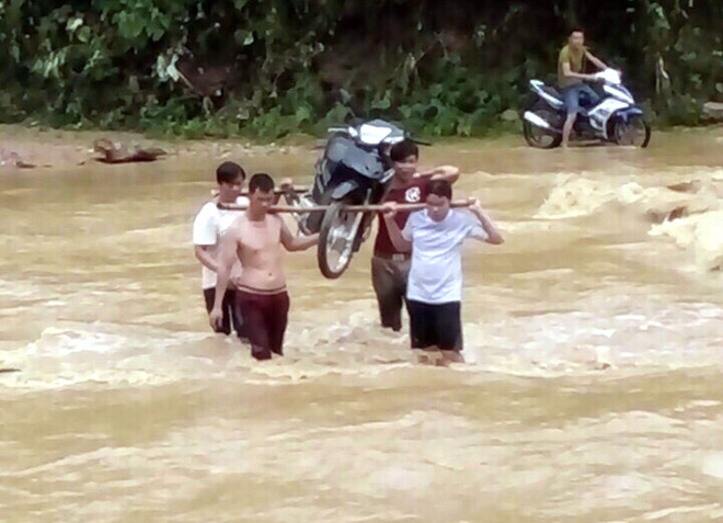 Người tham gia giao thông phải thuê người dân khênh xe máy qua các dập tràn đường ĐT 185 đoạn xã Xuân Vân, Kiến Thiết, huyện Yên Sơn với giá 50.000 đồng/lượt. (Ảnh: Quang Đán/TTXVN) Mưa lũ gây sạt lở nhiều nhà dân và tuyến đường tại Tuyên Quang ảnh 1