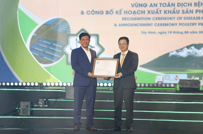 Ông Nguyễn Văn Long, Cục Trưởng Cục Thú y (phải) trao chứng nhận vùng an toàn dịch bệnh cho đại diện lãnh đạo Ủy ban Nhân dân huyện Tân Châu, tỉnh Tây Ninh. (Ảnh: Giang Phương/TTXVN) ttxvn_an toan dich benh 1.jpg