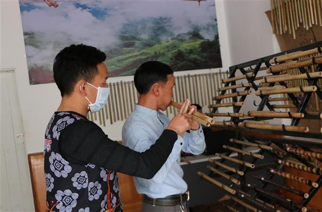 Anh Ma A Cháng, ở bản Sin Câu, xã Giang Ma, huyện Tam Đường hướng dẫn khách hàng thổi sáo. (Ảnh: Việt Hoàng/TTXVN) Chuyện khởi nghiệp của những chàng trai đam mê 'giữ lửa' sáo Mông ảnh 1