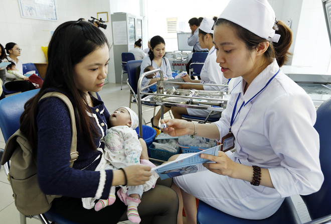 Nhân viên y tế làm thủ tục tiêm chủng cho trẻ tại Trung tâm Y tế Dự phòng Hà Nội. (Ảnh: Dương Ngọc/TTXVN) Vắcxin ComBe Five sẽ thay thế Quinvaxem trong tiêm chủng mở rộng ảnh 1