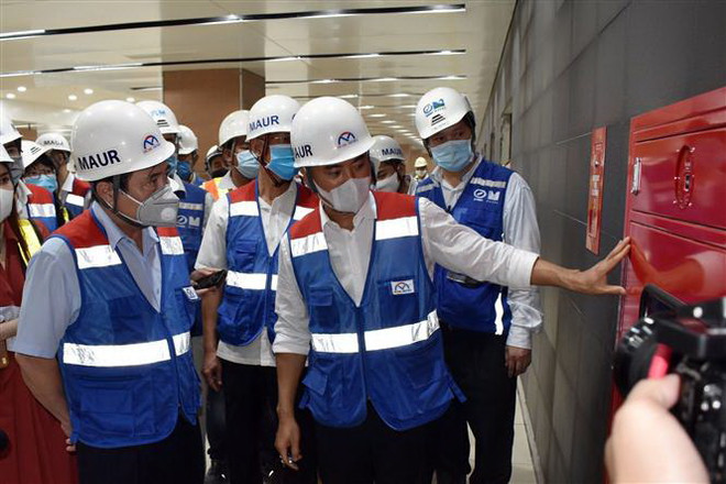 Lãnh đạo Ban Quản lý đường sắt đô thị giới thiệu hệ thống phòng cháy chữa cháy tại ga Nhà hát Thành phố của Dự án metro số 1. (Ảnh: Tiến Lực/TTXVN) Nỗ lực sớm đưa đoàn tàu metro Bến Thành-Suối Tiên về Việt Nam ảnh 1