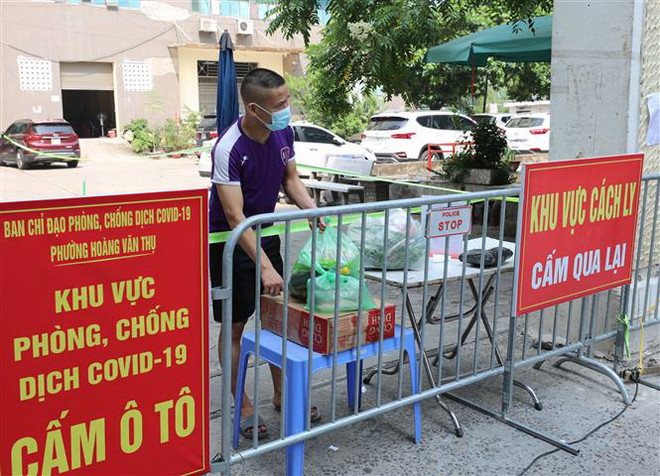 Người dân nhận đồ chuyển từ bên ngoài vào. (Ảnh: Thanh Tùng/TTXVN) Hà Nội: Phong tỏa 3 cụm tòa nhà tại Đền Lừ vì liên quan đến 16 ca F0 ảnh 1