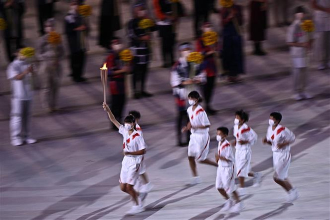 Các vận động viên rước đuốc Olympic tại lễ khai mạc Olympic Tokyo 2020 ở Tokyo, Nhật Bản, ngày 23/7. (Ảnh: AFP/TTXVN) Olympic Tokyo 2020: Ấn tượng lễ khai mạc đầy nhân văn và tình đoàn kết ảnh 1
