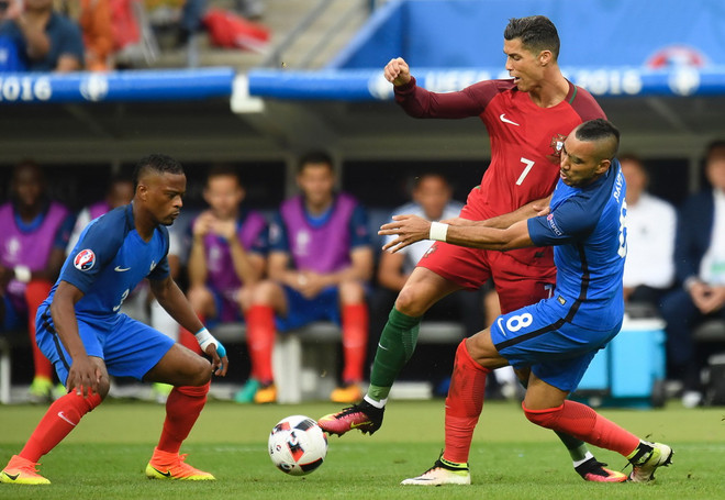 Hậu vệ Patrice Evra (trái) và tiền đạo Dimitri Payet (trái) của Pháp truy cản quyết liệt tiền đạo Bồ Đào Nha Cristiano Ronaldo. (Nguồn: AFP/TTXVN) Những điểm nhấn không thể bỏ qua tại Vòng chung kết EURO 2016 ảnh 1