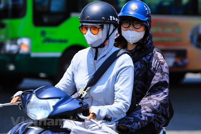 Người dân mặc áo chống nắng khi tham gia giao thông. (Ảnh: Hoài Nam/Vietnam+) Bắc Bộ tiếp tục nắng nóng gay gắt ở nhiều nơi, có nơi trên 38 độ C ảnh 1