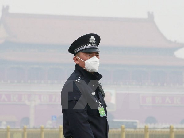 Cảnh sát Trung Quốc đeo khẩu trang tránh khói mù ô nhiễm tại thủ đô Bắc Kinh. (Ảnh: Reuters/TTXVN) Trung Quốc ban bố cảnh báo vàng về tình trạng ô nhiễm khói mù ảnh 1