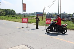Lực lượng chức năng tại Sóc Sơn lập rào chắn và hướng dẫn người và phương tiện chuyển sang lộ trình khác nhằm đảm bảo an toàn. (Ảnh: Vũ Quang/TTXVN)