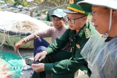 Bộ đội Biên phòng và ngư dân tại đảo Cù Lao Chàm (xã Tân Hiệp, thành phố Đà Nẵng) theo dõi thông tin về bầu cử trên điện thoại. (Ảnh: Anh Dũng/TTXVN)