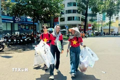 Các tình nguyện viên nhóm Xanh Việt Nam tham gia dọn vệ sinh đường phố sau buổi tổng duyệt diễu binh. (Ảnh: TTXVN phát)