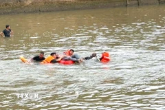 Lực lượng chức năng đưa thi thể nạn nhân đuối nước vào bờ. (Ảnh: TTXVN phát)