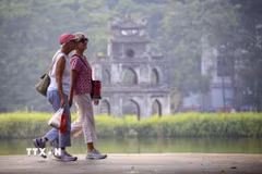 Du khách nước ngoài đi dạo bên hồ Hoàn Kiếm. (Ảnh: Tuấn Đức/TTXVN)