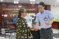 Cán bộ Trung tâm phục vụ hành chính công thành phố Bắc Ninh hướng dẫn người dân làm thủ tục hành chính. (Ảnh: Thái Hùng/TTXVN)