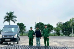 Đối tượng Hoàng Văn Bình (đứng giữa) (sinh năm 1991, trú tại xã Đông Ngũ, tỉnh Quảng Ninh) cùng tang vật và phương tiện bị lực lượng Biên phòng bắt giữ. (Ảnh: TTXVN phát)