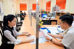 Hướng dẫn người dân làm thủ tục nộp thuế trước bạ. (Ảnh: Phạm Hậu/TTXVN)