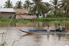 Phụ huynh đưa đón con đi học bằng xuồng. (Ảnh: Tuấn Phi/TTXVN)