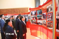 Bộ trưởng Bộ Thông tin, Văn hóa và Du lịch Lào Suansavanh Viyaket cùng các đại biểu tham quan Triển lãm ảnh. (Ảnh: Xuân Tú/TTXVN)