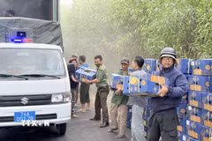 Các lực lượng chức năng và người dân khẩn trương bốc dỡ các thùng sầu riêng trên xe container bị cháy. (Ảnh: TTXVN phát)
