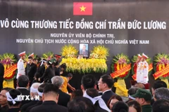Nghi lễ thả hoa vào huyệt. (Ảnh: Phạm Cường/TTXVN)