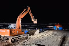 Xe máy xúc vận chuyển những tấm thép lớn để làm đường cho xe cần cẩu hạng nặng tiếp hiện trường tàu gặp nạn. (Ảnh: Nguyên Linh/TTXVN)