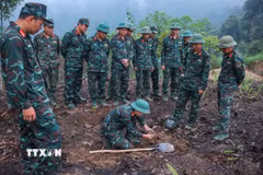 Các thành viên Đội tìm kiếm, quy tập hài cốt liệt sĩ sử dụng máy dò mìn để đảm bảo khu vực tìm kiếm "sạch" trước khi tiến hành tìm kiếm. (Ảnh: Hoàng Hiếu/ TTXVN)