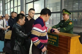 Cán bộ, chiến sĩ Bộ đội Biên phòng hướng dẫn du khách làm thủ tục xuất nhập cảnh tại Cửa khẩu quốc tế Móng Cái, Quảng Ninh. (Ảnh: PV/Vietnam+)