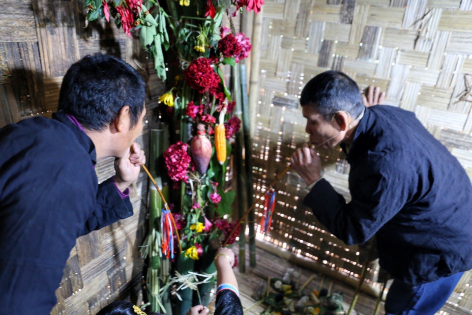 Thầy cúng và gia chủ uống rượu cần tại buổi lễ. (Ảnh: Tuấn Đức/TTXVN)