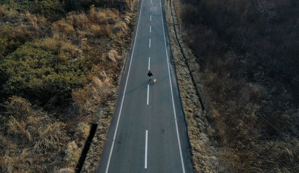 Kato dắt chú chó cứu hộ Pochi trên con đường vắng nối giữa các khu vực cấm ở Namie, tỉnh Fukushima. "Tôi không muốn rời đi, tôi thích sống ở những ngọn núi này," Kato nói. (Ảnh: Reuters)